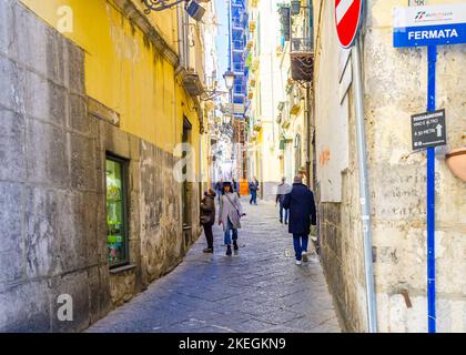 April 04 2022 - Neapel Italien - die überfüllte Straße eines Morgens mit vielen Motorroller und Leuten, die an alten bunten Gebäuden vorbeilaufen, um zu arbeiten Stockfoto