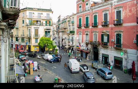 April 04 2022 - Neapel Italien - die überfüllte Straße eines Morgens mit vielen Motorroller und Leuten, die an alten bunten Gebäuden vorbeilaufen, um zu arbeiten Stockfoto
