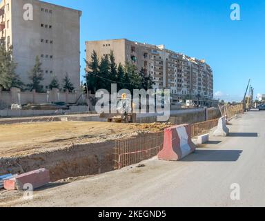Tunnelbaustelle in der Nationalstraße RN 41. Ein Mann, der einen Baggerlader mit Baumaschinen, Lastwagen, Baggern und Kränen fährt. Stockfoto