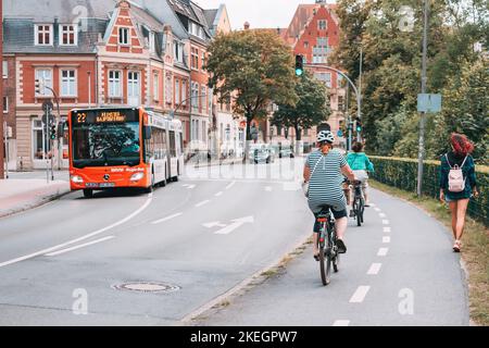 25. Juli 2022, Münster, Deutschland: Radfahrer fahren auf dem Radweg auf den Straßen der Stadt. Öffentliche Verkehrsmittel Bus auf der Strecke in Vorstadt Stockfoto