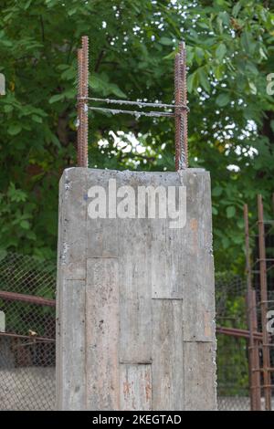 Vertikale Aufnahme der neu gebauten Betonsäule für das zukünftige Haus aus nächster Nähe - umgeben von grünen Bäumen. Stockfoto