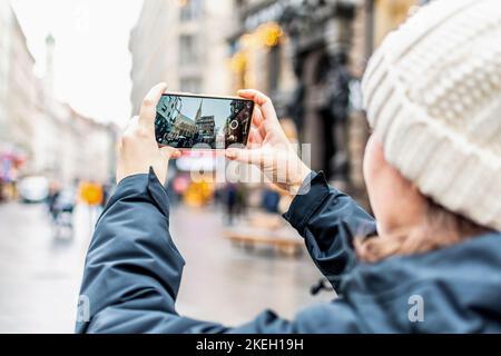 Nahaufnahme eines Touristen, der mit einem Mobiltelefon ein Foto vom Stephansdom in Wien, Österreich, macht Stockfoto