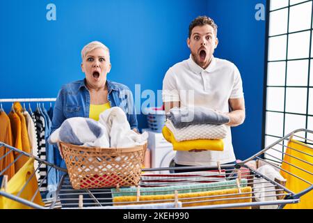 Hispanische Mutter und Sohn hängen Kleidung an der Wäscheleine Angst und schockiert mit Überraschung und erstaunt Ausdruck, Angst und aufgeregt Gesicht. Stockfoto