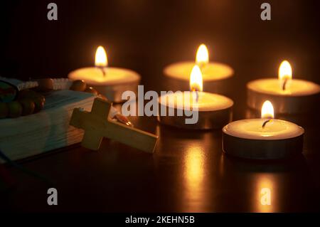 Heiliger Rosenkranz und Bibel auf dunklem Kerzenlicht Hintergrund mit anpassbarem Platz für Text oder Ideen. Speicherplatz kopieren. Stockfoto