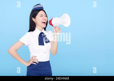 Die Frau, die eine Stewardess im Flugzeug hat, wurde auf blauem Hintergrund isoliert und schrie durch das Megaphon Stockfoto