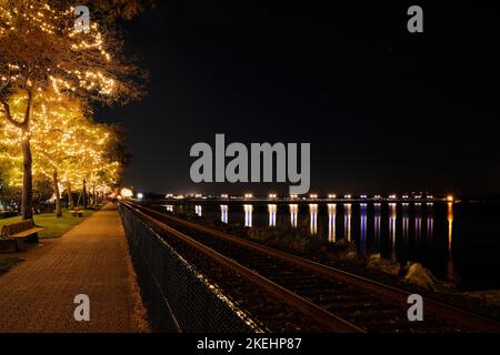 Winterabend am Ufer des White Rock. Farbenfrohe Lichter am Pier bilden Starbursts und hübsche Lichter an den Bäumen sorgen für Glanz. Stockfoto