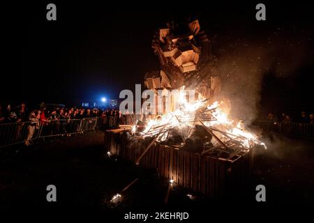 East Hoathly, Großbritannien. 12.. November 2022. Lagerfeuer der Erinnerung: Jährliche Karnevalsfeiern von East Hoathly an diesem Wochenende zum Gedenken an den Waffenstillstand- und Erinnerungssonntag. Die Sussex-Dorfbewohner tragen in einer Reihe von Prozessionen zur Lagerfeuerskulptur, die in diesem Jahr einen Löwen mit seiner Pfote auf einer Krone zeigt, um der Königin zu gedenken, flammende Feuerbanner und Fackeln. Kredit: Jim Holden/Alamy Live Nachrichten Stockfoto