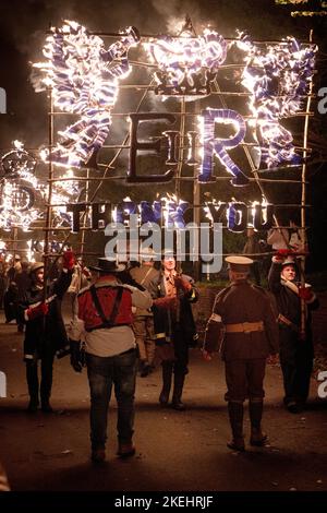 East Hoathly, Großbritannien. 12.. November 2022. Lagerfeuer der Erinnerung: Jährliche Karnevalsfeiern von East Hoathly an diesem Wochenende zum Gedenken an den Waffenstillstand- und Erinnerungssonntag. Die Sussex-Dorfbewohner tragen in einer Reihe von Prozessionen zur Lagerfeuerskulptur, die in diesem Jahr einen Löwen mit seiner Pfote auf einer Krone zeigt, um der Königin zu gedenken, flammende Feuerbanner und Fackeln. Kredit: Jim Holden/Alamy Live Nachrichten Stockfoto