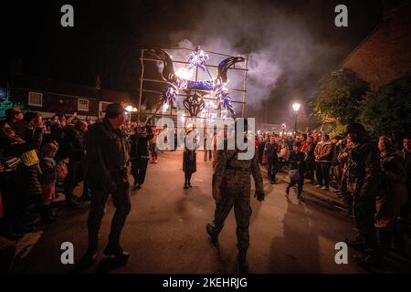 East Hoathly, Großbritannien. 12.. November 2022. Lagerfeuer der Erinnerung: Jährliche Karnevalsfeiern von East Hoathly an diesem Wochenende zum Gedenken an den Waffenstillstand- und Erinnerungssonntag. Die Sussex-Dorfbewohner tragen in einer Reihe von Prozessionen zur Lagerfeuerskulptur, die in diesem Jahr einen Löwen mit seiner Pfote auf einer Krone zeigt, um der Königin zu gedenken, flammende Feuerbanner und Fackeln. Kredit: Jim Holden/Alamy Live Nachrichten Stockfoto