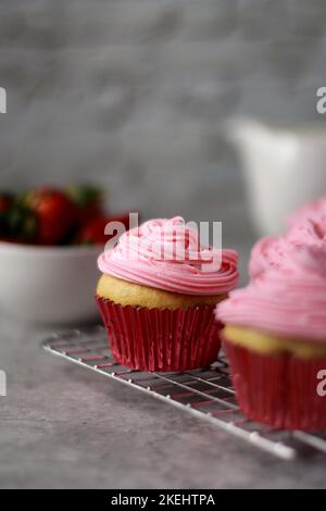 Nahaufnahme von Vanille-Muffins, die mit rosa Buttercreme-Zuckerguss auf der Oberseite verziert sind Stockfoto