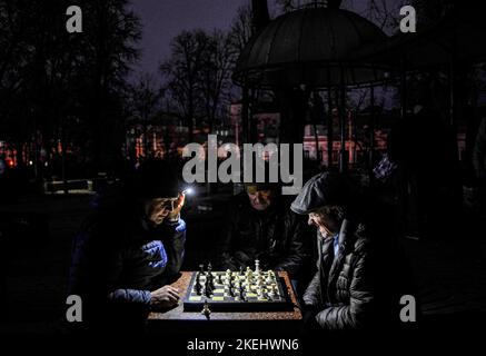 Kiew, Ukraine. 12.. November 2022. Männer sahen Schach durch eine Taschenlampe in einem Park in Kiew spielen. Die russische Armee führte massive Raketen- und Kamikaze-Drohnenangriffe auf die ukrainische Energieinfrastruktur durch. Schätzungen von Experten zufolge sind mittlerweile 40 % der Energieinfrastruktur zerstört oder beschädigt. Nach schweren Schäden am Stromnetz in vielen Städten der Ukraine führte die National Power Company Ukrenergo Notfälle und stündliche Stromausfälle ein. Kredit: SOPA Images Limited/Alamy Live Nachrichten Stockfoto