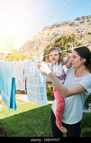 Eine Mutter und eine Tochter hängen ihre Wäsche draußen auf. Stockfoto