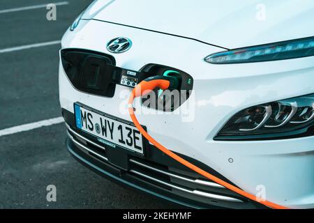 26. Juli 2022, Münster, Deutschland: Hyundai modernes Elektroauto wird auf dem Parkplatz aufgeladen. Umweltbewusstsein und umweltfreundlicher Verkehr und der Transit Stockfoto