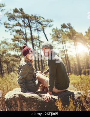 Wir lieben es hier draußen zu sein. Rückansicht eines liebevollen jungen Paares, das beim Wandern eine Pause einnahm. Stockfoto