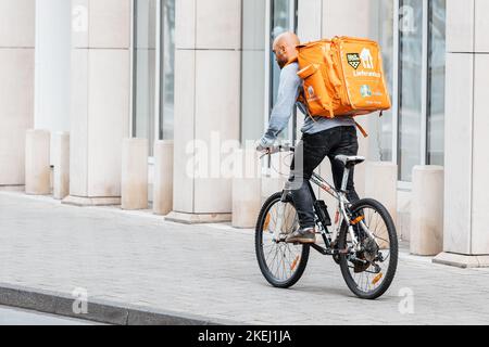 26. Juli 2022, Münster, Deutschland: Ein männlicher Kurier auf einem Fahrrad mit einem großen Rucksack mit Essen trägt eine Bestellung, die über eine mobile Anwendung auf eine cl gemacht wurde Stockfoto