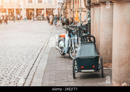 Ein Kinderwagen-Anhänger für ein Fahrrad ist auf einer Stadtstraße geparkt Stockfoto