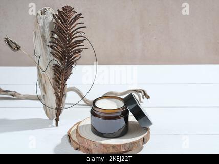 Braunglas Gesicht Creme Glas, unbranded Hautpflege-Produkt auf Holz Podium mit natürlichen trendigen Stillleben Komposition. Schönheit und Selbstpflege Stockfoto