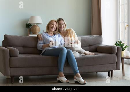 Frau verbringt Zeit mit Tochter, die sich auf dem Sofa ausruht und Tee trinkt Stockfoto