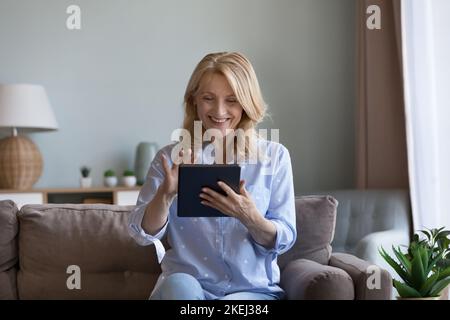 Glückliche, reife Frau, die zu Hause ein digitales Tablet nutzt Stockfoto