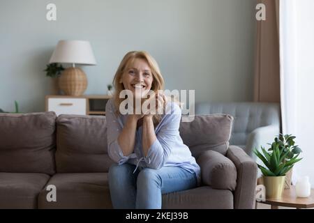 Hübsche Frau mittleren Alters posiert für Bild auf dem Sofa sitzen Stockfoto