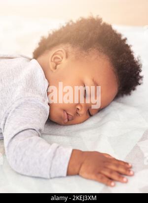 Schlafen Sie süß kostbar ein. Ein kleiner Junge schlafen auf einem Bett. Stockfoto