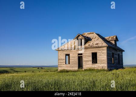 Ein lange ungenutztes Schulhaus auf Ackerland unter dem blauen Himmel in Ost-Idaho, USA Stockfoto