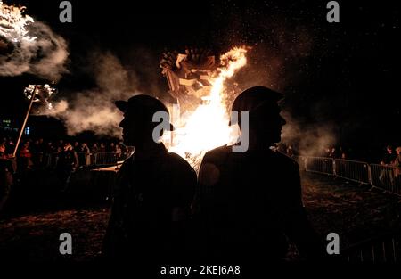 East Hoathly, Großbritannien. 12.. November 2022. Lagerfeuer der Erinnerung: Jährliche Karnevalsfeiern von East Hoathly an diesem Wochenende zum Gedenken an den Waffenstillstand- und Erinnerungssonntag. Die Sussex-Dorfbewohner tragen in einer Reihe von Prozessionen zur Lagerfeuerskulptur, die in diesem Jahr einen Löwen mit seiner Pfote auf einer Krone zeigt, um der Königin zu gedenken, flammende Feuerbanner und Fackeln. Kredit: Jim Holden/Alamy Live Nachrichten Stockfoto