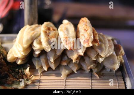 Stapel von Gyoza oder gebratenen Knödel auf dem Display zum Verkauf auf der Straße Stockfoto