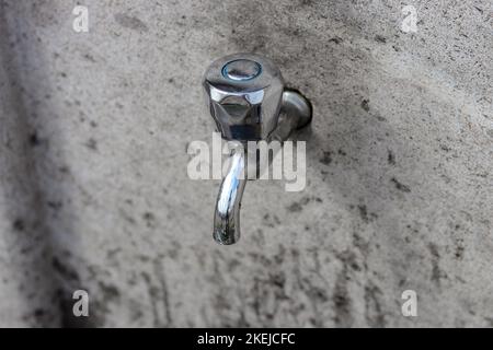 Wasserhahn an einer Steinwand montiert. Draufsicht auf den Wasserhahn. Stockfoto