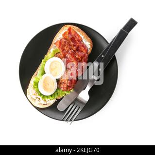 Teller mit leckeren Toast mit gekochtem Ei und gebratenem Speck auf weißem Hintergrund Stockfoto