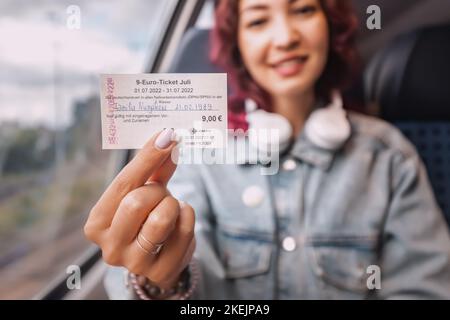 27. Juli 2022, Münster, Deutschland: Ein Studentinnen hält einen Monat lang ein günstiges 9-Euro-Ticket für alle Transportarten in Deutschland in den Händen. Stütze o Stockfoto