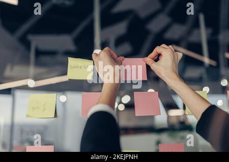 Geschäftsfrau Hand klebt Haftnotizen auf Motivationsbrett im Büro Stockfoto