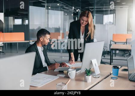 Zwei multiethnische Mitarbeiter arbeiten zusammen und analysieren die Charts im Büro Stockfoto