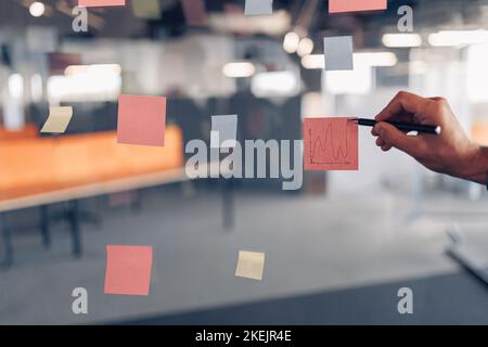 Businessman Hand's schreibt in modernen Büros auf Haftnotizen an Bord Stockfoto