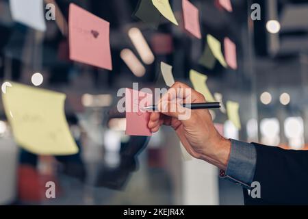 Geschäftsfrau Hand klebt Haftnotizen auf dem Business Board im Büro Stockfoto