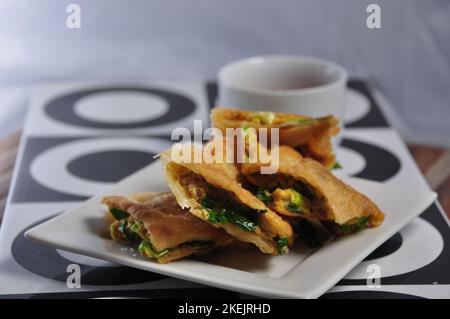 Martabak Telor oder Martabak Telur. Pikantes, gebratenes Gebäck, gefüllt mit Ei, Fleisch und Gewürzen Stockfoto