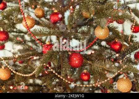 Teil eines Weihnachtsbaums, der mit Lichtern und roten und goldenen Kugeln geschmückt ist Stockfoto