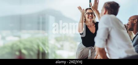 Geschäftsfrau gibt einem männlichen Kollegen bei einem Meeting fünf. Geschäftsleute erreichen bei einer Besprechung im Sitzungssaal fünf. Stockfoto