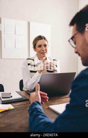 Geschäftsfrau, die während eines Vorstellungsgesprächs in ihrem Büro die Antwort eines Bewerbers anhört. Weibliche Personaldirektorin, die ein Treffen mit einer candi in die engere Wahl hat Stockfoto