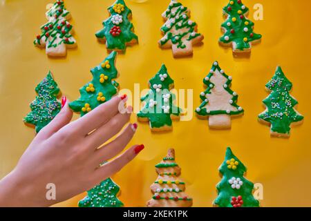 Lebkuchenkekse auf dem goldenen Hintergrund mit Mädchenhand Stockfoto