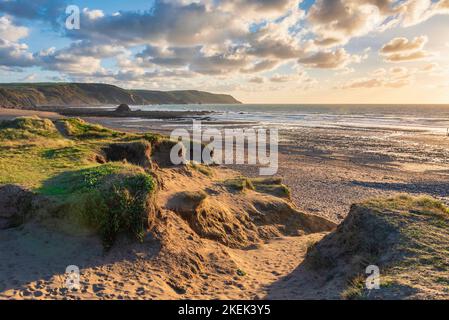 Schönes Landschaftsbild im Sommer bei Sonnenuntergang von Widemouth Bay in Devon England mit goldenem Stundenlicht am Strand Stockfoto