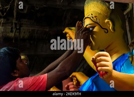 Kalkutta, Indien - 25. September 2022: Ein Handwerker mittleren Alters beschäftigt in seiner Werkstatt in Kumortuli. Er konzentriert sich tief auf die Malerei des Auges eines Be Stockfoto