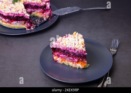 Heringsalat unter einem Pelzmantel. Traditioneller russischer, vielschichtiger Salat aus Hering, Rüben, Kartoffeln, Karotten und Eiern. Nahaufnahme, grauer Hintergrund. Stockfoto