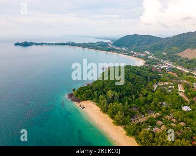 Luftdrohnenansicht der Insel Koh Lanta - der lange Strand. Berühmter tropischer Strand mit weißem Sand und türkisfarbenem Meer. Die Inselberge im Hintergrund. Stockfoto