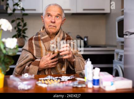 Alter Mann mit vielen medizinischen Pillen und Kapseln in den Händen Stockfoto