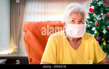Asiatische ältere Frau trägt eine Maske Prävention von COVID-19 Feiern Sie Neujahr und Weihnachten allein. Stockfoto