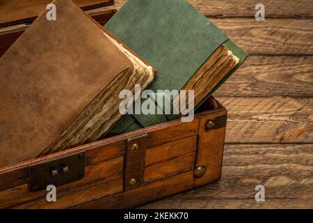 Alte Bücher oder Zeitschriften im Retro-Dekokoffer auf rustikalem Holztisch Stockfoto