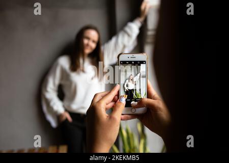 Zwei junge Frauen fotografieren und Videos von einander auf dem Smartphone auf einer Terrasse Stockfoto