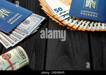 Ukrainische biometrische Pässe mit Dollar und Euro liegen auf schwarzem Hintergrund Stockfoto
