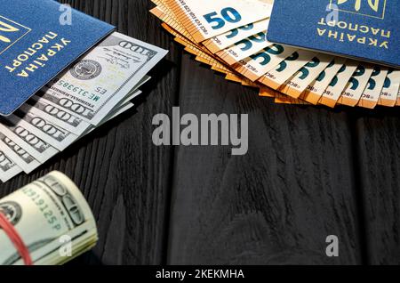 Ukrainische biometrische Pässe mit Dollar und Euro liegen auf schwarzem Hintergrund Stockfoto